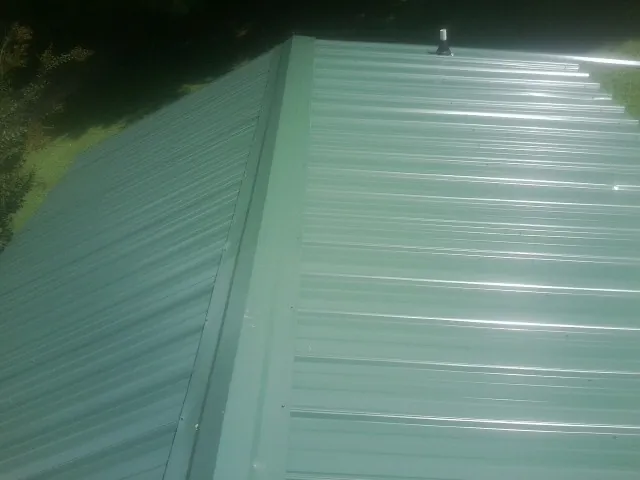 New green metal panels meeting at the ridge of a roof — Flat Roof Repair work by our crew in North Port