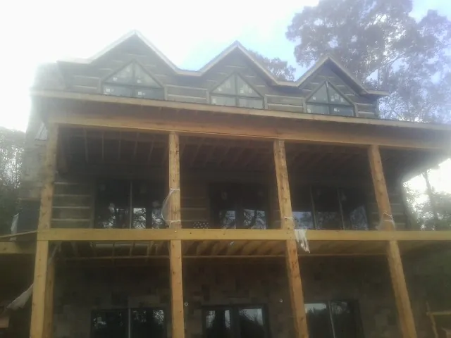 Dormers and porch framing on a large log home under construction — Roof Coating work by our crew in North Port