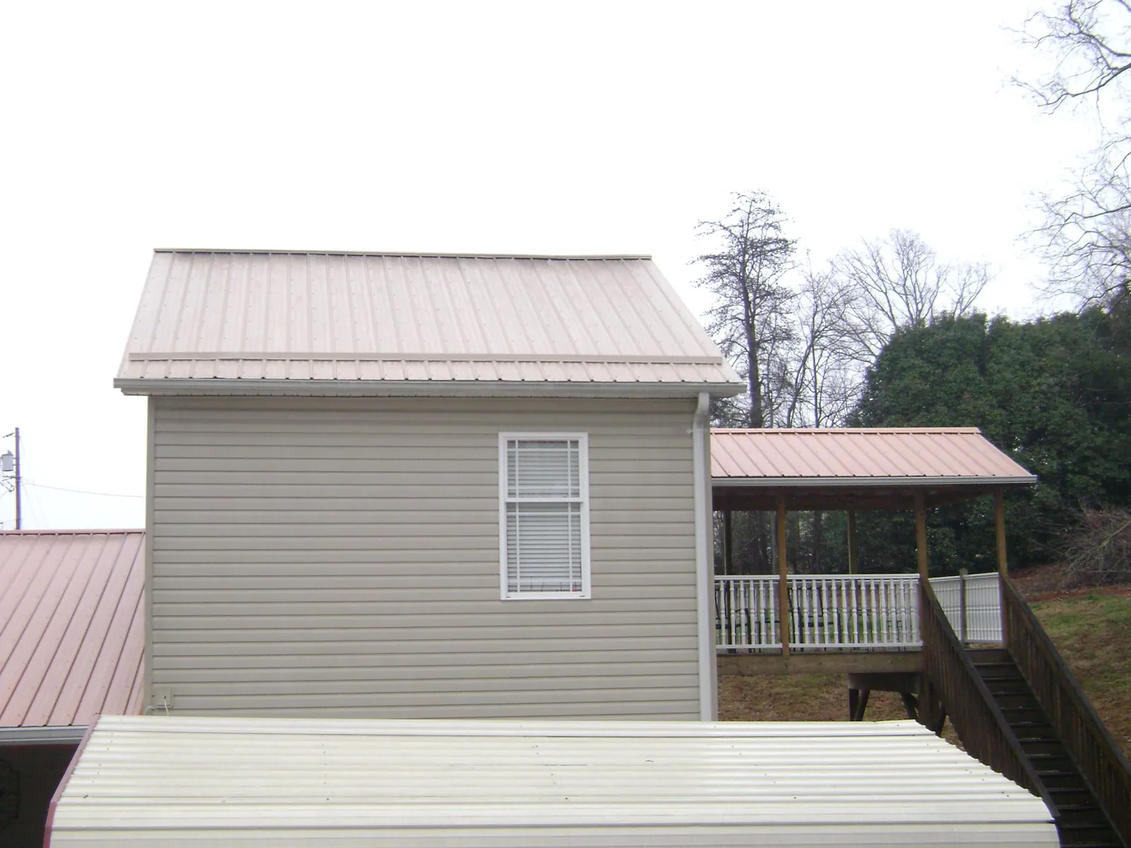 Tan metal roofs on a two story addition and attached porch, from a Roof Replacement job in North Port